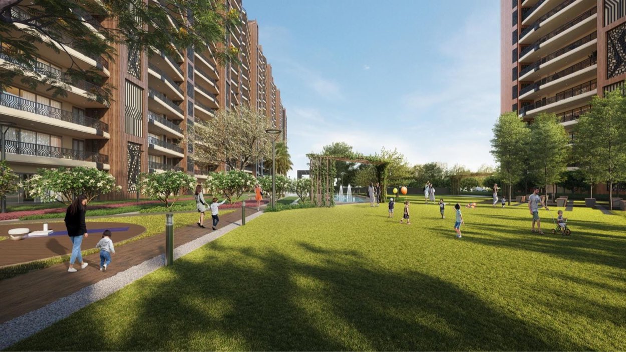 Parents and children on a large central lawn between residential towers at Vamana Arvindam, Zirakpur